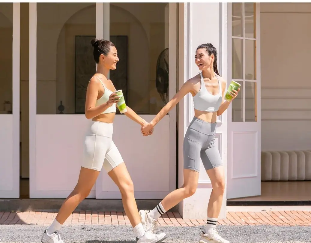 Two friends walking hand in hand with smoothies