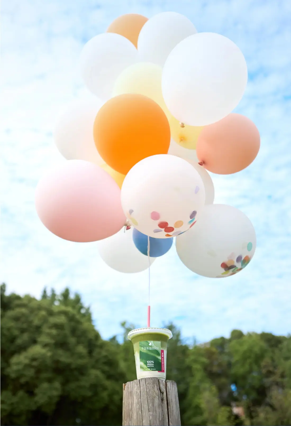Matcha drink on a tree stump tied to pastel balloons